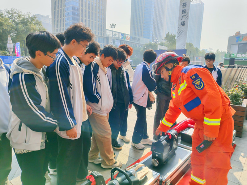 学生在消防装备展示区参观并聆听消防员讲解