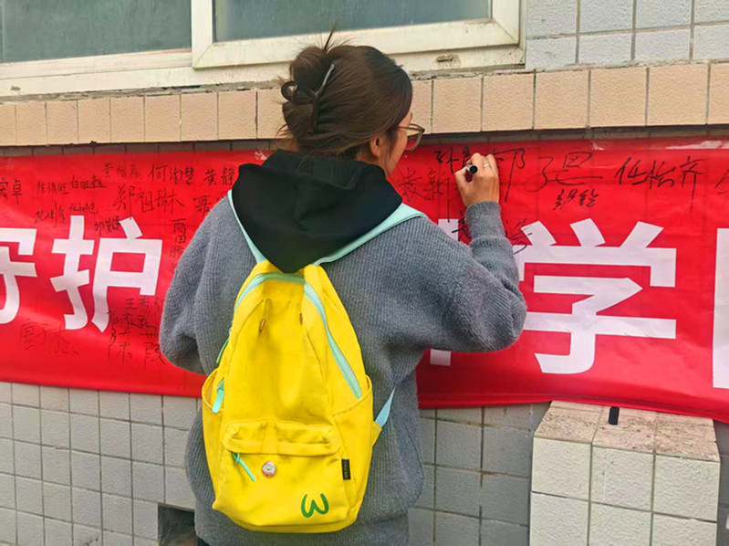 学生在防艾主题横幅上郑重签名