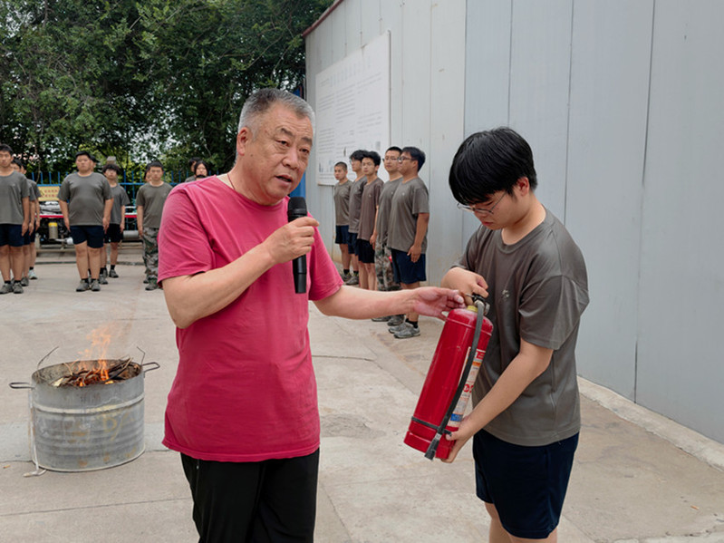 后勤安保处干事魏孔宇现场演示干粉灭火器 “提、拔、握、压” 操作方法。