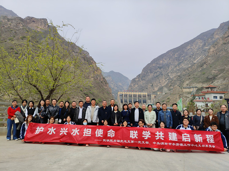 全体党员与青年学子驻足群山环抱的水利工程前合影定格初心