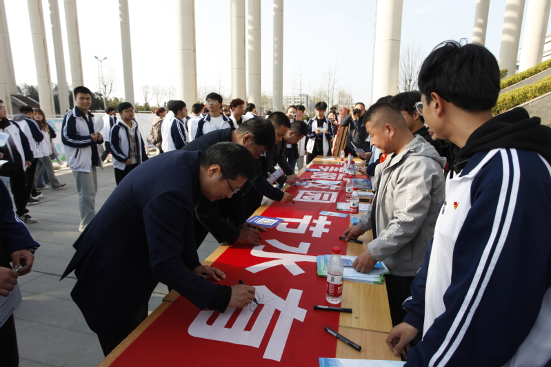 学校领导和与会嘉宾在宣传横幅上签字