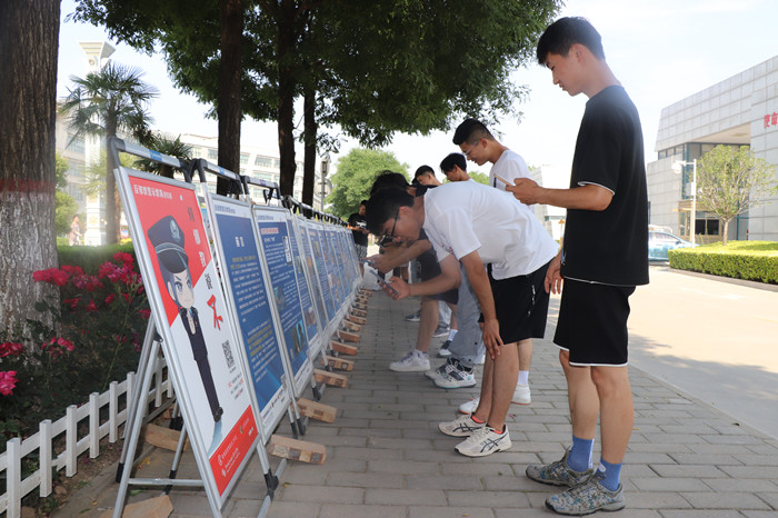 学生观看反邪教宣传展板并扫码关注“中国反邪教”微信公众号